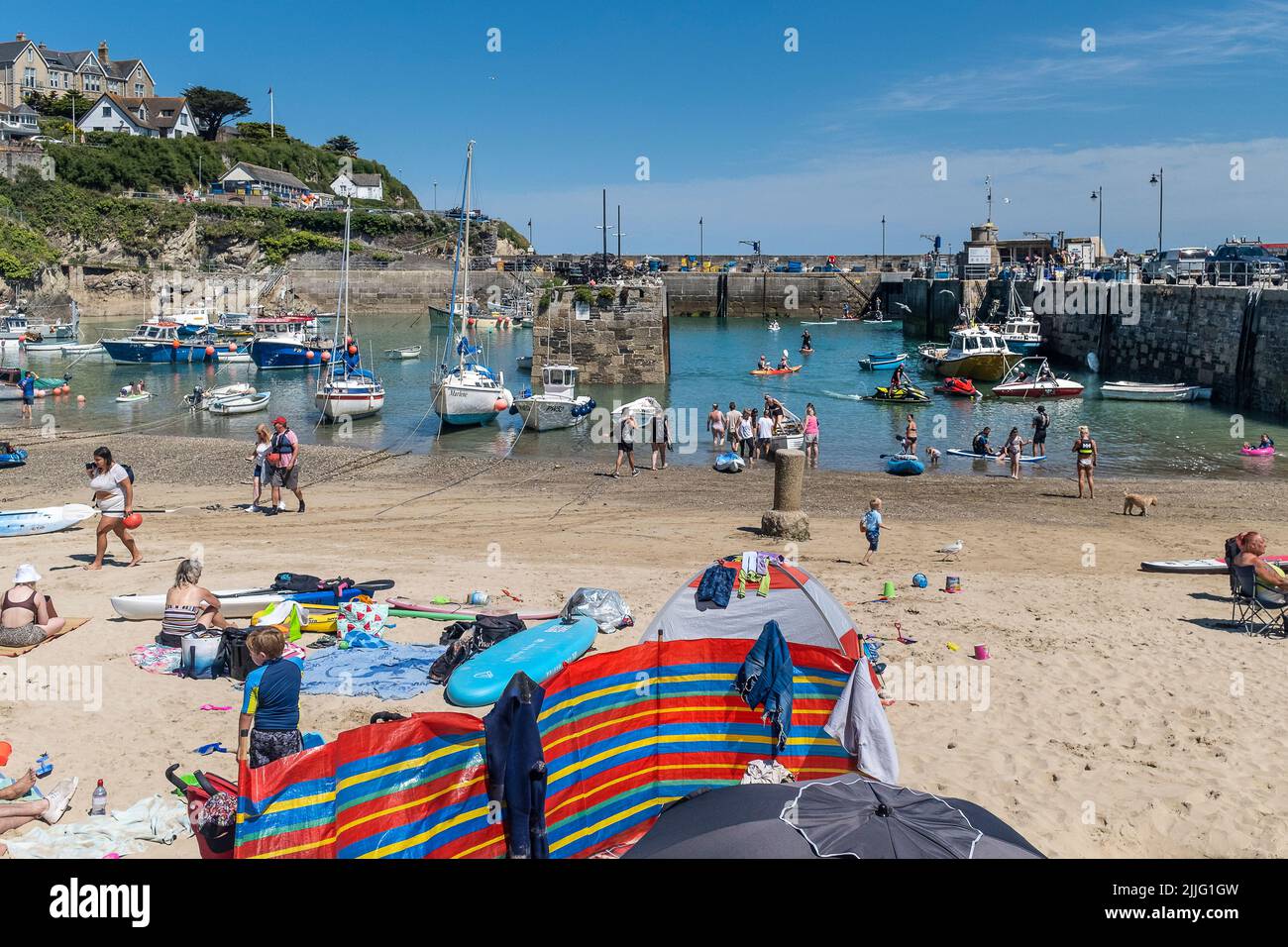 Holidaymakers enjoying the glorious sunshine on a staycation in the picturesque Newquay Harbour in Cornwall in England in the UK. Stock Photo
