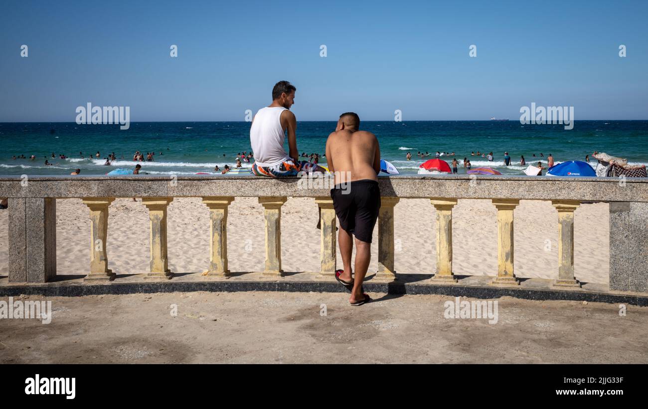 Two men chat next to Bou Jaafar Beach in Sousse, Tunisia. Stock Photo