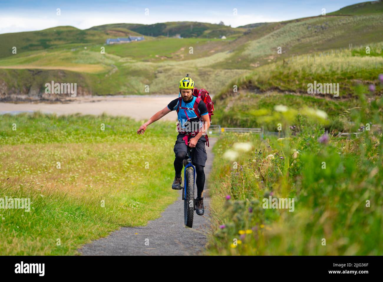 Bettyhill, Scotland, UK. 26 July 2022. Luke Evison riding his unicycle at Bettyhill in the Scottish highlands during his Scotland on One Wheel charity cycle odyssey. Luke ,39, from Bristol is riding solo and unsupported for approximately 225 miles across the Scottish Highlands to raise money for the charities Parkinson’s UK and Mind UK. Luke’s brother was diagnosed with Parkinson’s 6 years ago. Luke finishes his trip at Thurso. Donations can be made at the following website. Collectionpot.com/pot/onewheel.   Iain Masterton/Alamy Live News Stock Photo