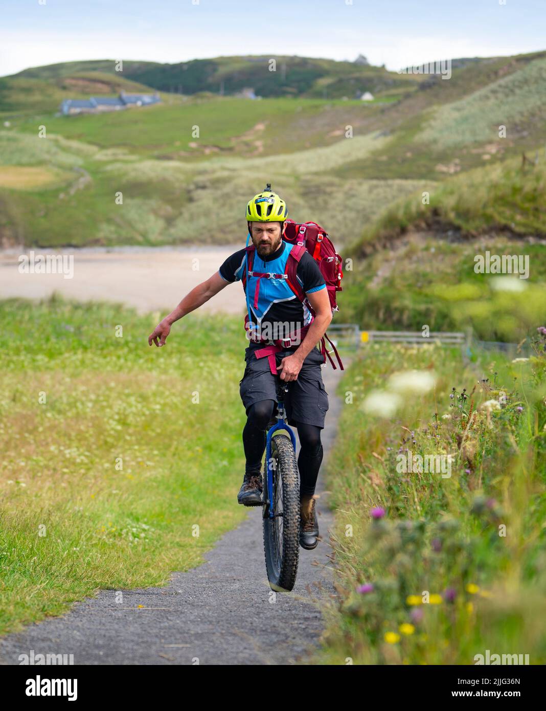 Bettyhill, Scotland, UK. 26 July 2022. Luke Evison riding his unicycle at Bettyhill in the Scottish highlands during his Scotland on One Wheel charity cycle odyssey. Luke ,39, from Bristol is riding solo and unsupported for approximately 225 miles across the Scottish Highlands to raise money for the charities Parkinson’s UK and Mind UK. Luke’s brother was diagnosed with Parkinson’s 6 years ago. Luke finishes his trip at Thurso. Donations can be made at the following website. Collectionpot.com/pot/onewheel.   Iain Masterton/Alamy Live News Stock Photo