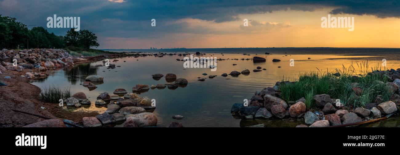 A beautiful colorful midsummer sunset in Northern Estonia (Haabneeme). Storm clouds can be seen on the background of beautiful rocks in a silent calm Stock Photo