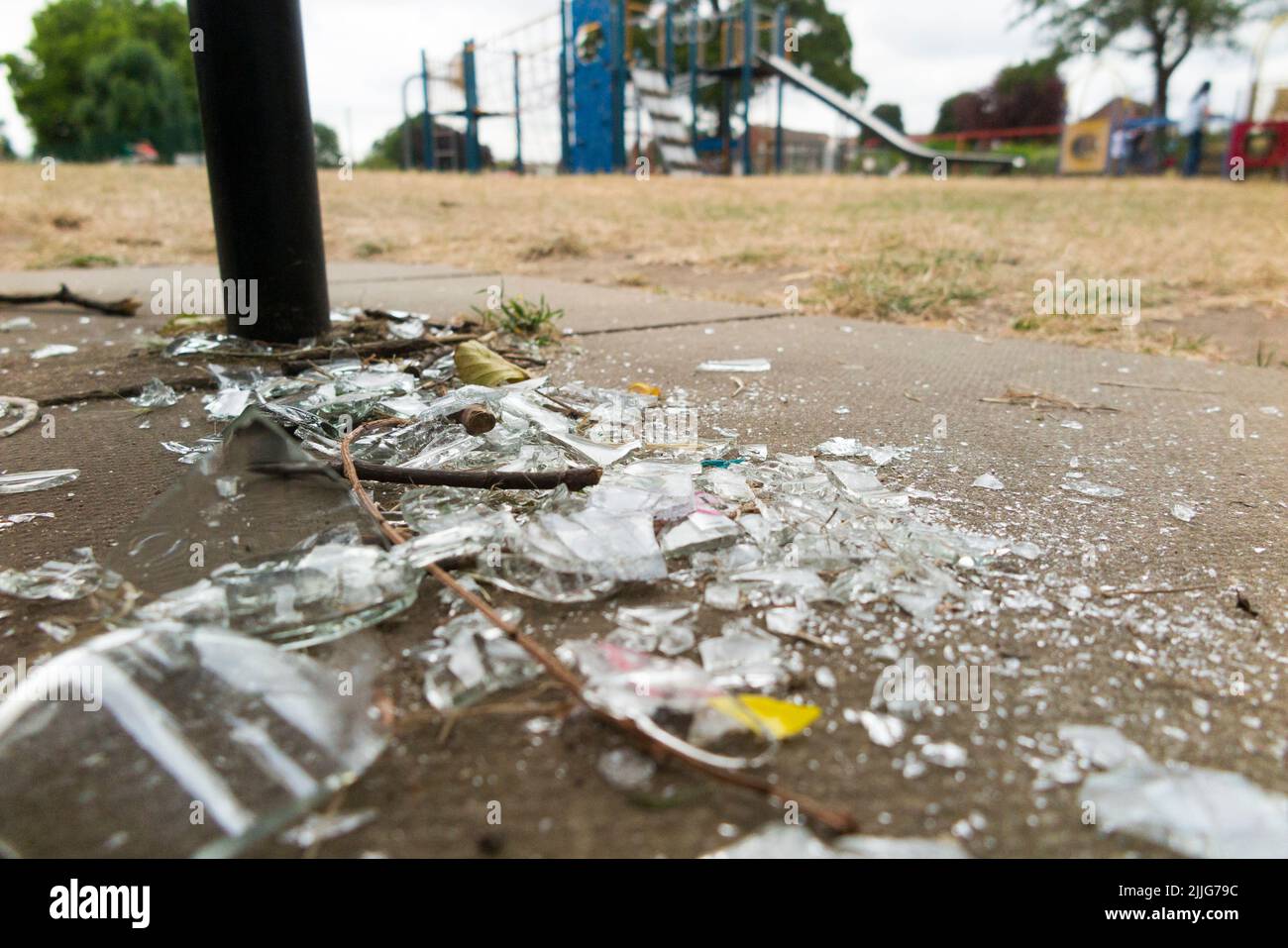 Broken glass bottle, left by vandal, in a children's child's playground. The sharp edges could easily severely cut a child. Twickenham. London. UK. (131) Stock Photo