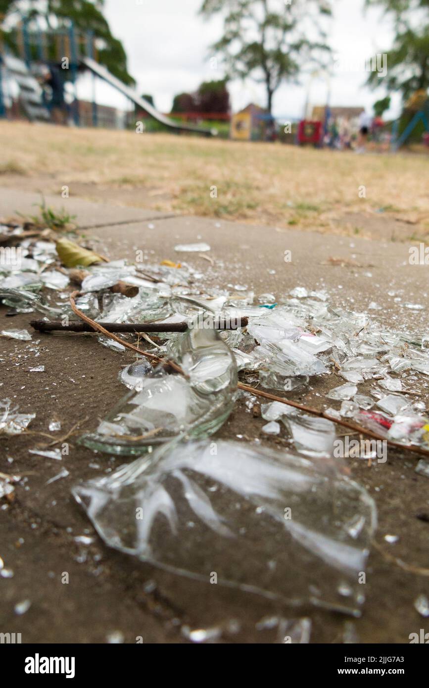 Broken glass bottle, left by vandal, in a children's child's playground. The sharp edges could easily severely cut a child. Twickenham. London. UK. (131) Stock Photo