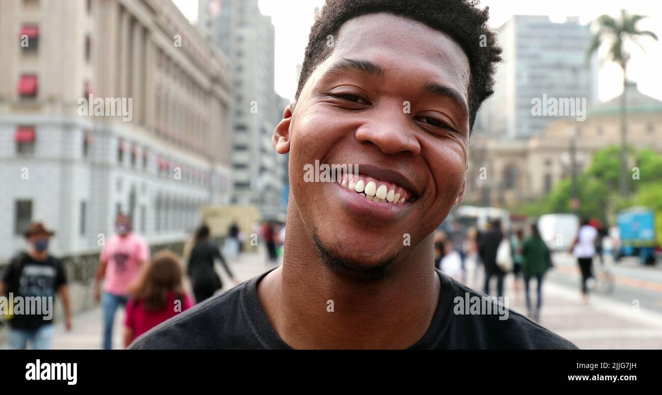 Trendy young black African man smiling at camera in downtown city, real ...