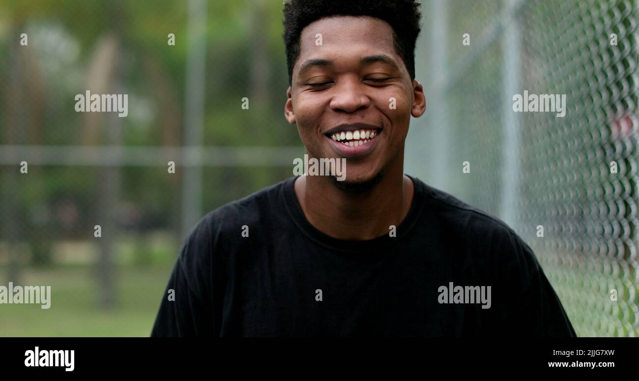 Young black man bursting laughing out loud outside. Person real life