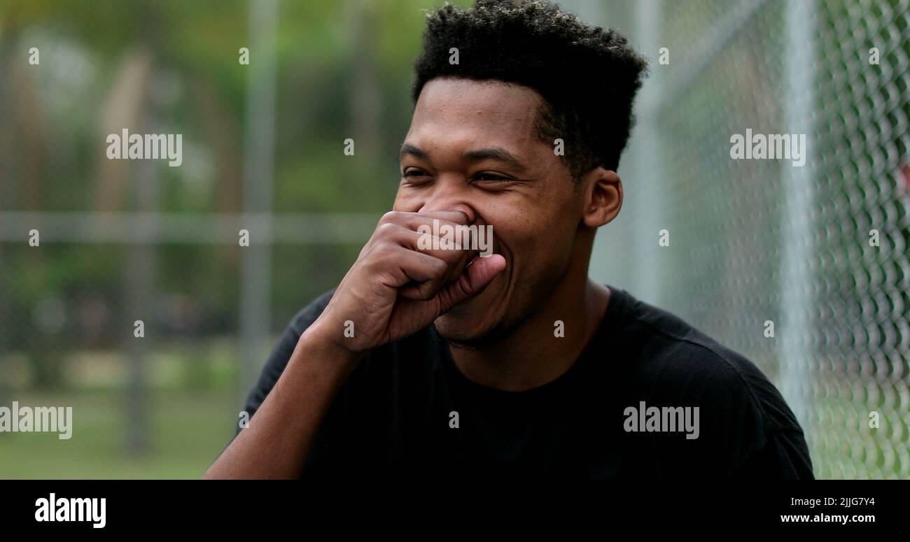 Young black man bursting laughing out loud outside. Person real life