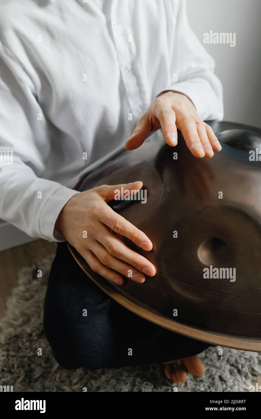 Man playing on hang drum, or Steel Drum, Hangpan, modern steel music instrument at home. Meditation music for relax . Close-up Stock Photo