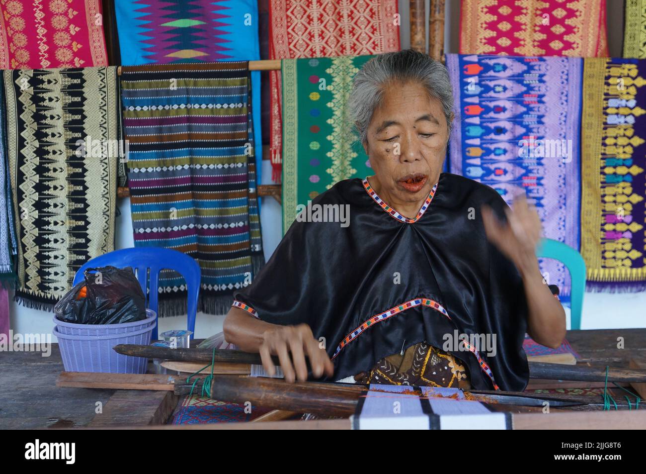 An old woman weave tenun Sasak fabrics with traditional process at Sukarara village, Lombok, Indonesia. Stock Photo