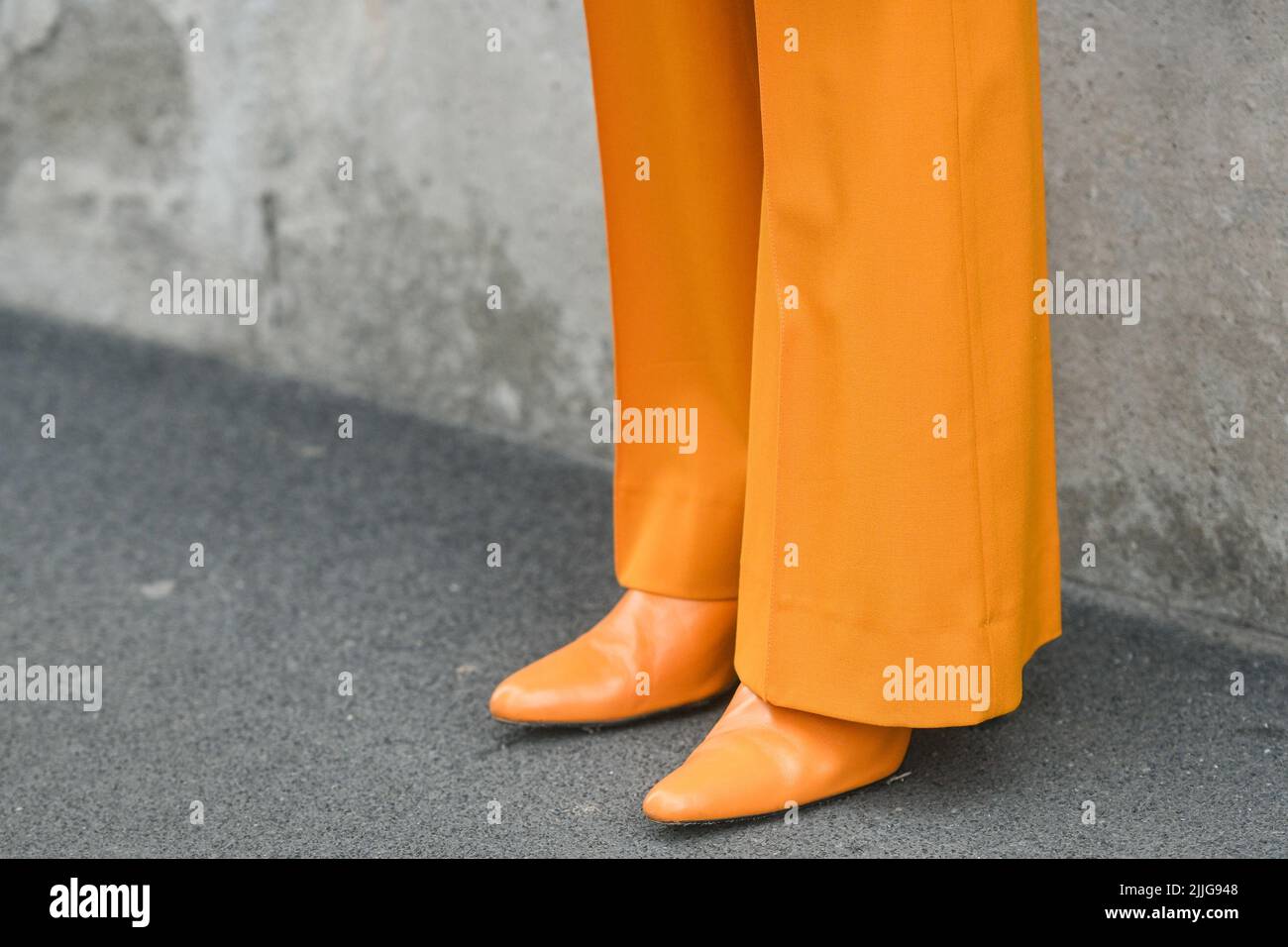 MILAN, ITALY - FEBRUARY 24, 2022: Woman wearing orange outfit: blazer jacket, pants and shoes. Stock Photo