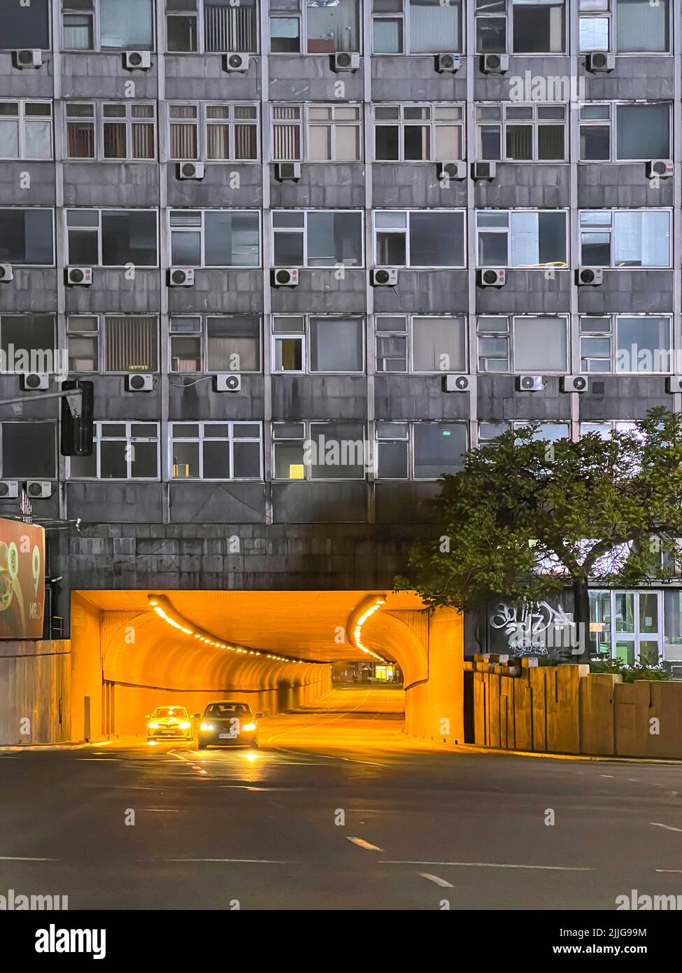 Facade of a building in Belgrade with street lights, a road tunnel under the building. Belgrade, Serbia - 2022, May 2. Stock Photo