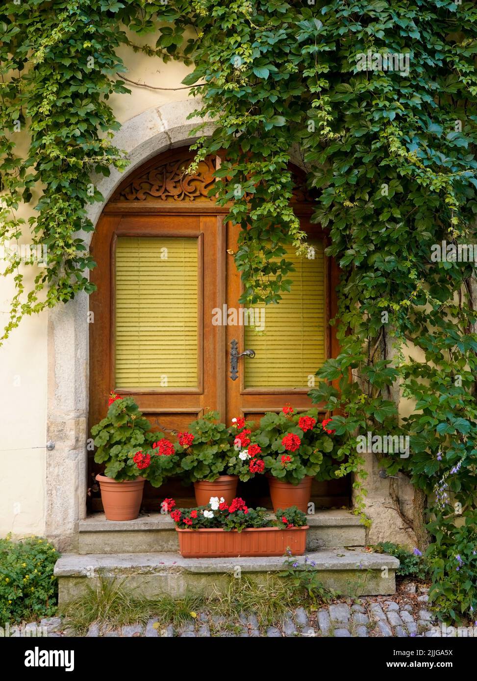 Old house and wooden door with red flowers Stock Photo - Alamy