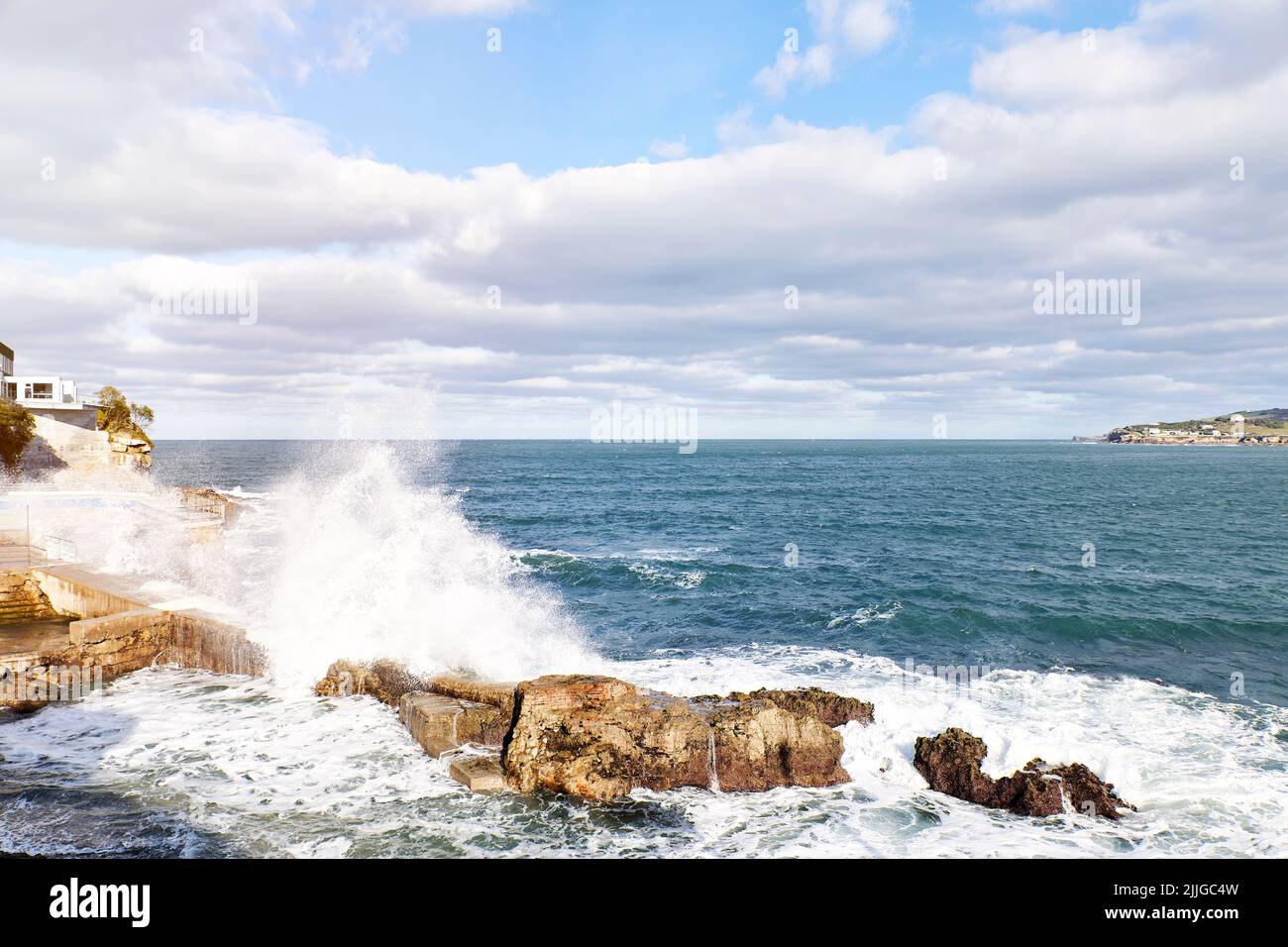 Waves breaking on rocks on the shore overlooking a coastal town. Concept travel, vacation Stock Photo