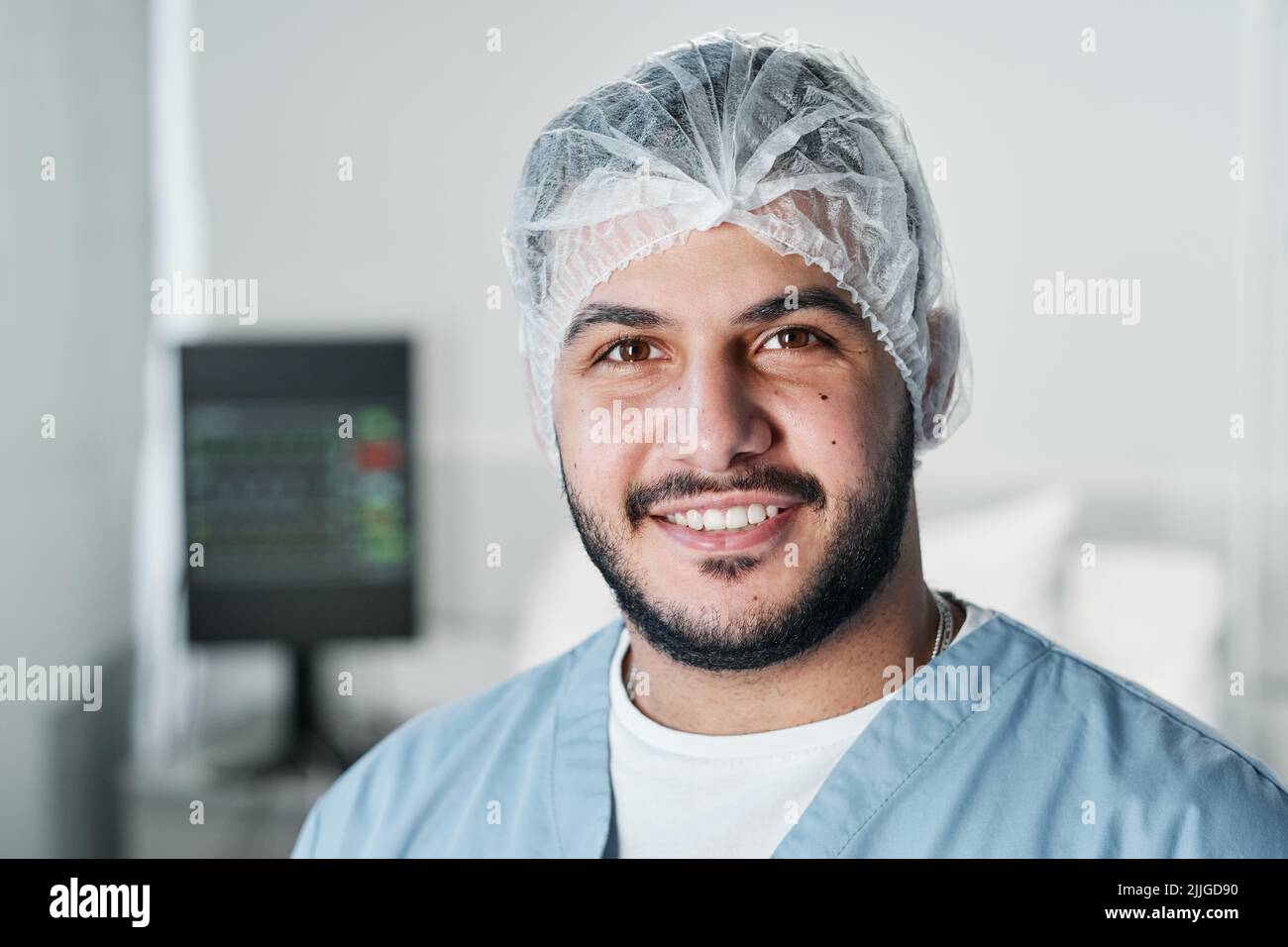 Horizontal close-up portrait of cheerful handsome Middle Eastern doctor with beard on face smiling at camera Stock Photo