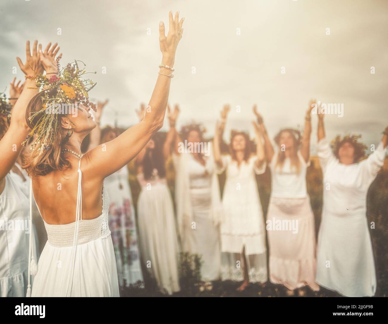 Women in flower wreath on sunny meadow, Floral crown, symbol of summer solstice. Stock Photo