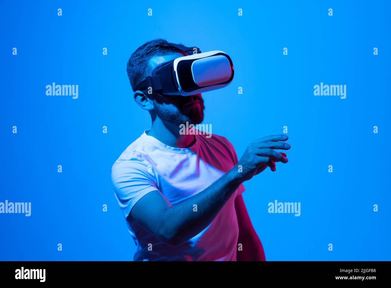 Young man close-up portrait wearing VR headset and speaking with a friends in metaverse while playing a games. Stock Photo