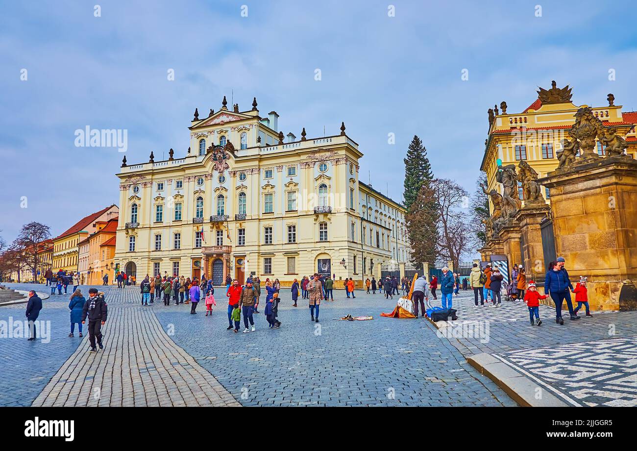 PRAGUE, CAZECH REPUBLIC - MARCH 6, 2022: Pedestrian Castle Square (Hradcanske Namesti) with Baroque Archbishop's Palace and stone gate of Prague Castl Stock Photo