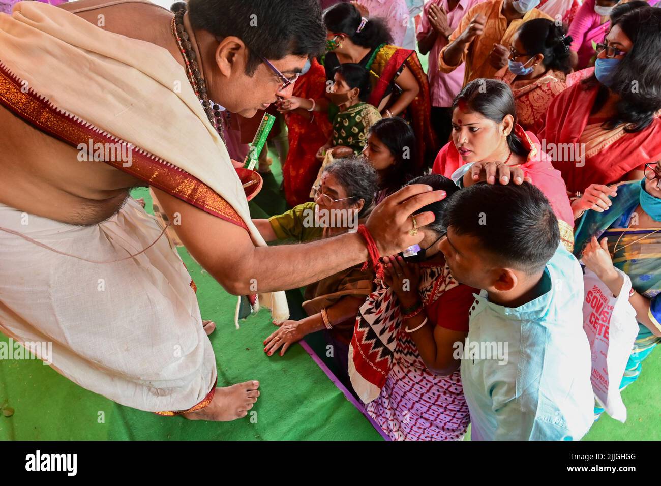 Howrah, West Bengal, India - 14th October 2021 : Hindu Purohit putting holy tilak on foreheads of devotees during pushpanjali puja to Goddess Durga. Stock Photo