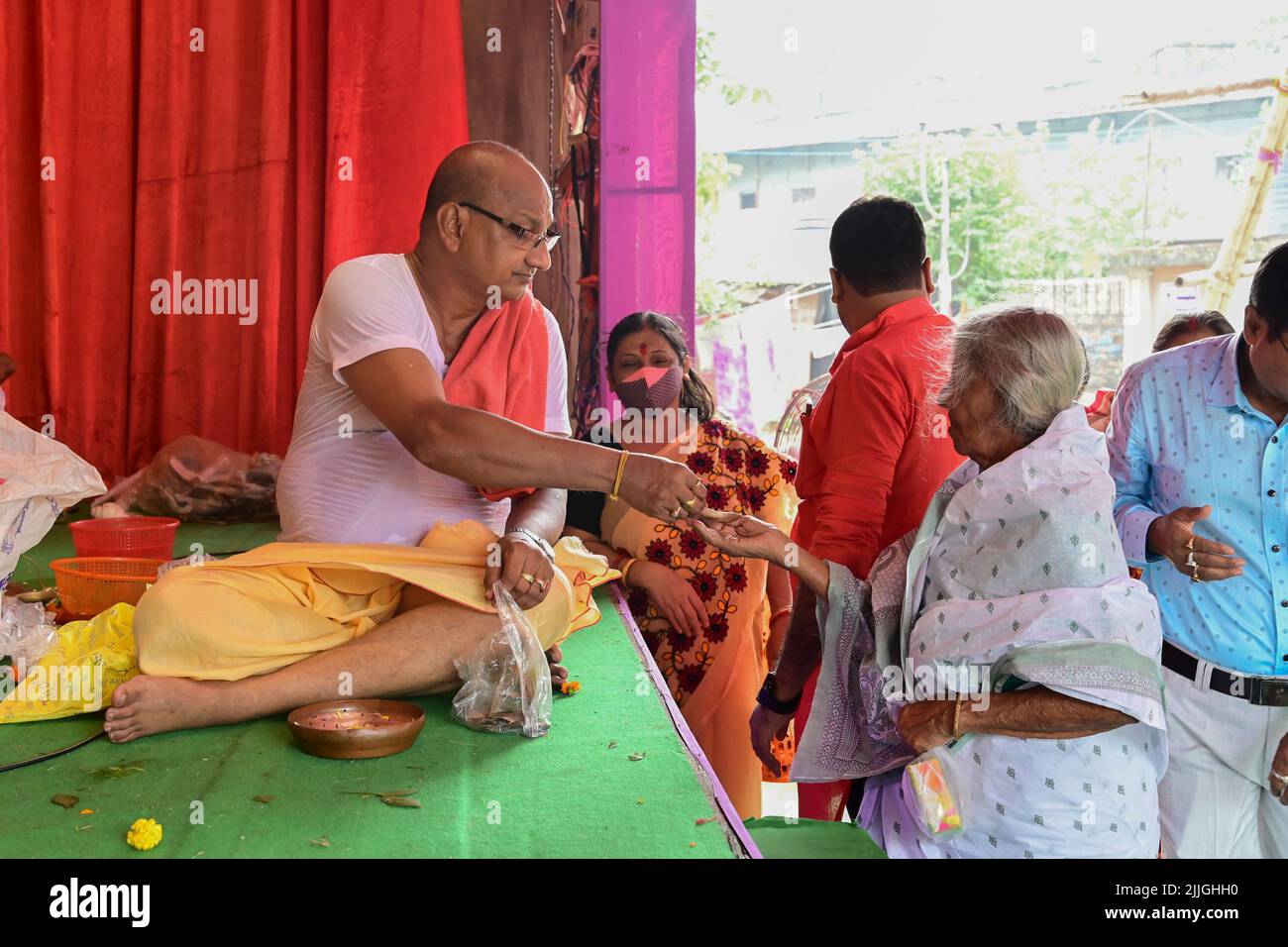 Howrah, West Bengal, India - 14th October 2021 : Hindu Purohit offering charanomrito, holy water and flower to devotees during pushpanjali to Durga. Stock Photo