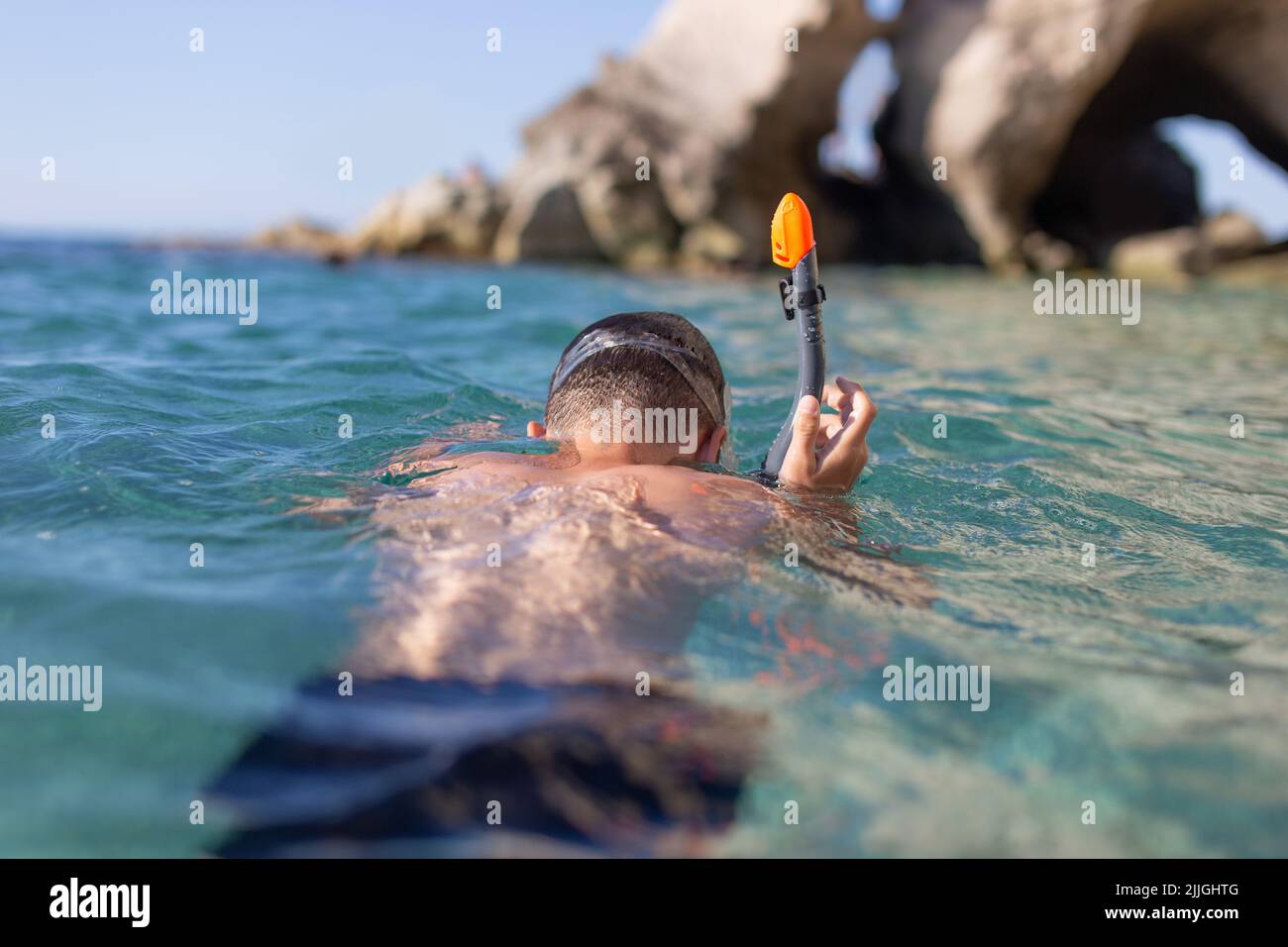 Young boy diving with pipe at rocky seashore at Calabria, Italy Stock Photo