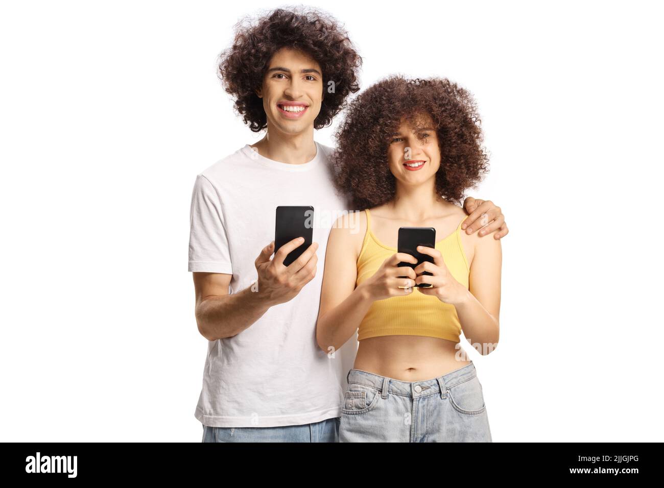 Guy and girl with curly hair holding smartphones and smiling at camera isolated on white background Stock Photo