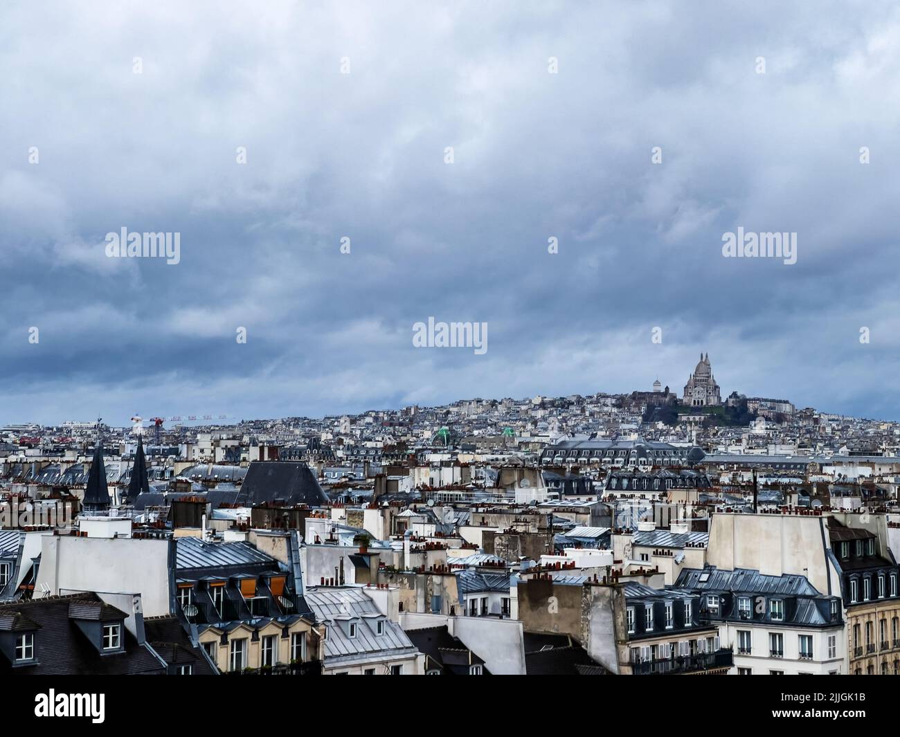 Paris downtown buildings over Montmartre Sacre Coeur Cathedral on moody weather day Stock Photo