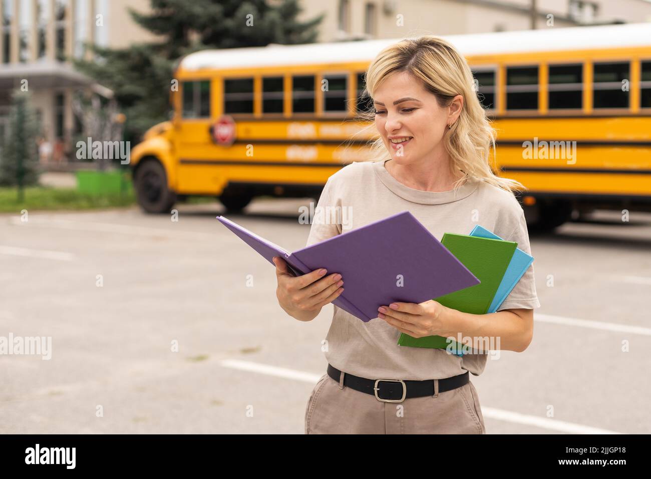 Portrait of cheerful teacher standing near the school bus Stock Photo ...