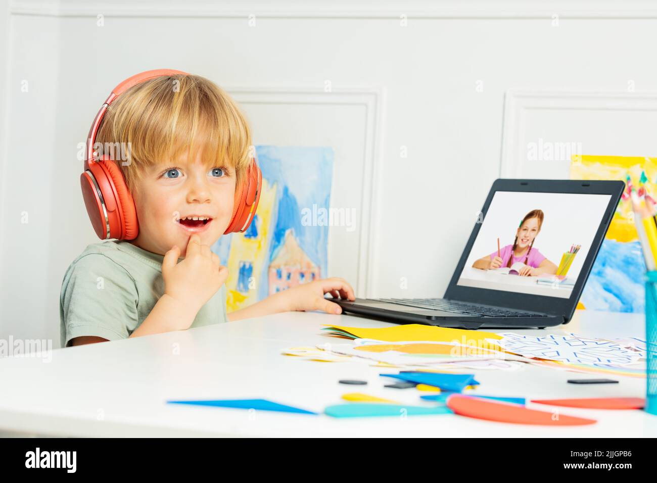 Smart smiling blond boy in headphones using laptop for education Stock ...