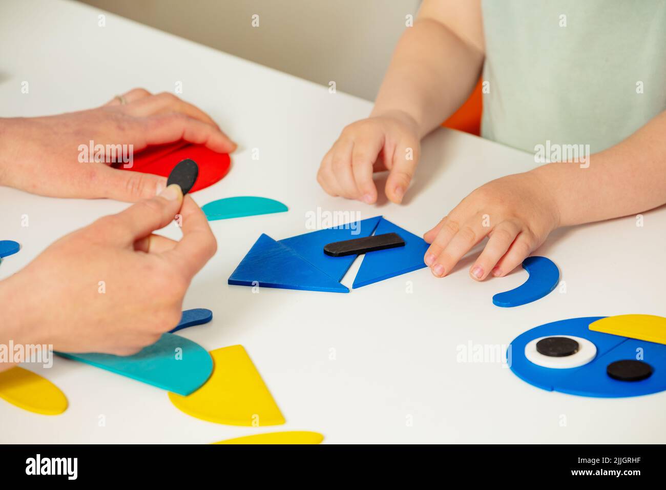 Girl child's hand put together shapes to create a house Stock Photo