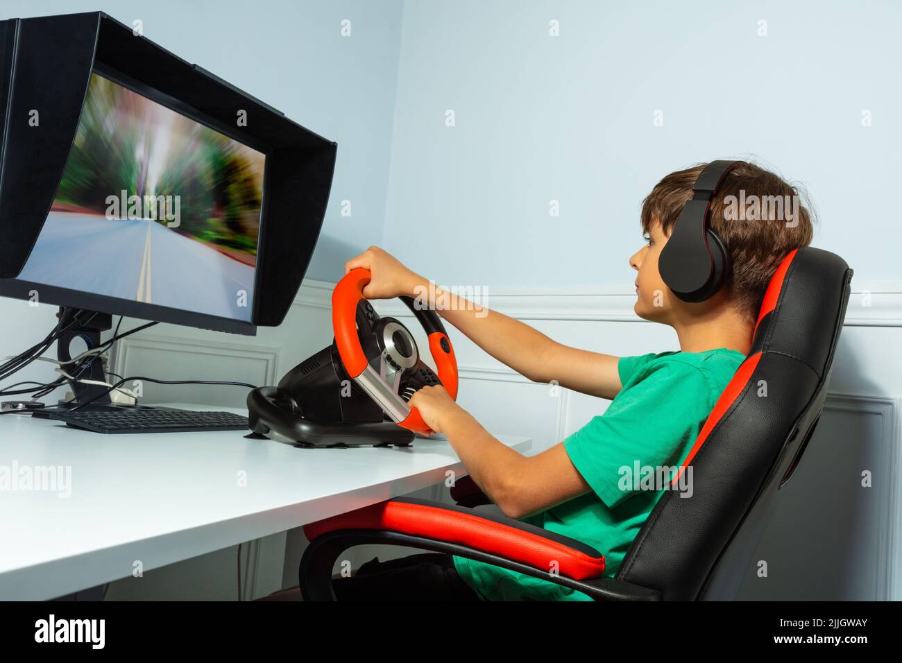 Side portrait of boy, hands on steering wheel play race game Stock Photo