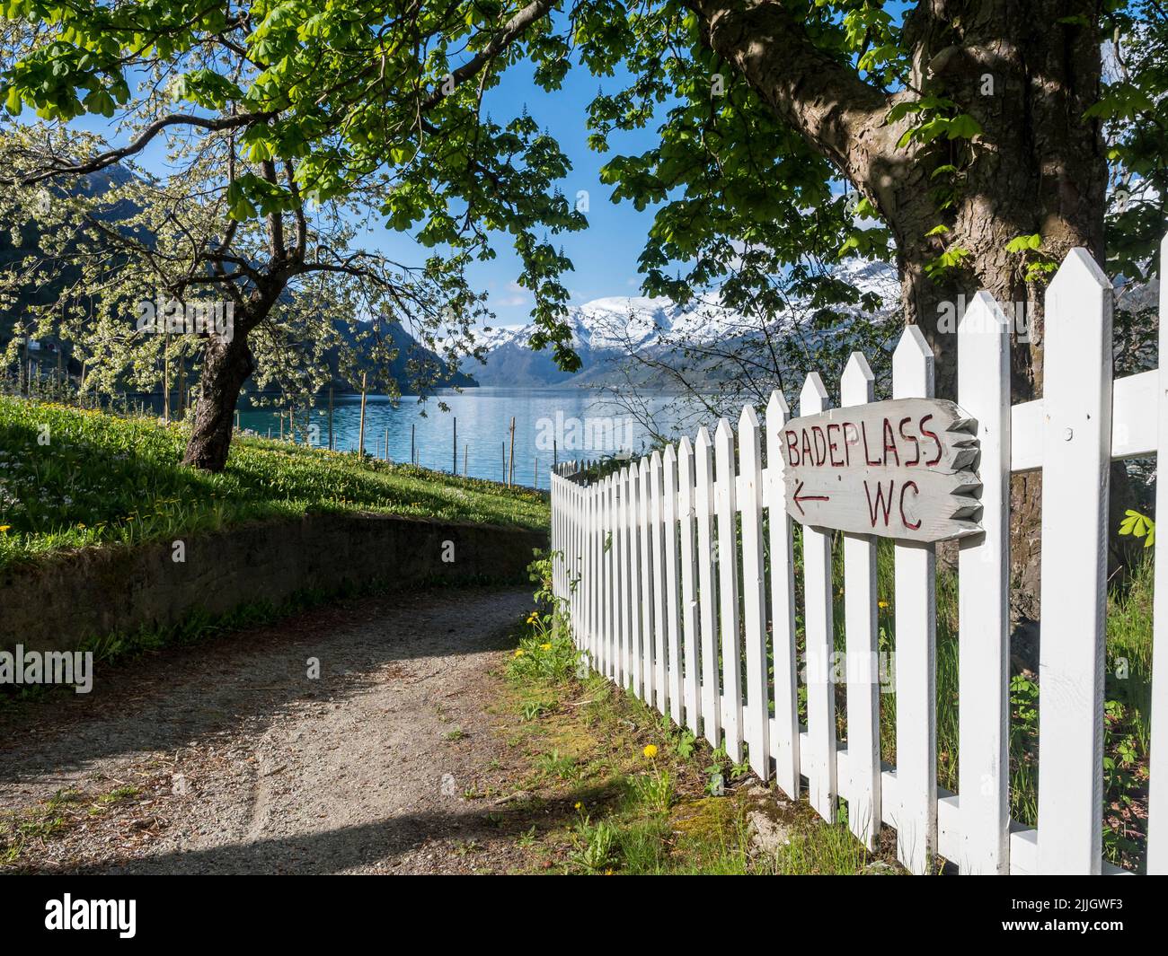 Signpost to a bathing place at the fjord,Sörfjord, branch of the Hardangerfjord, gras and trees, white fence, Ullensvang, Norway Stock Photo