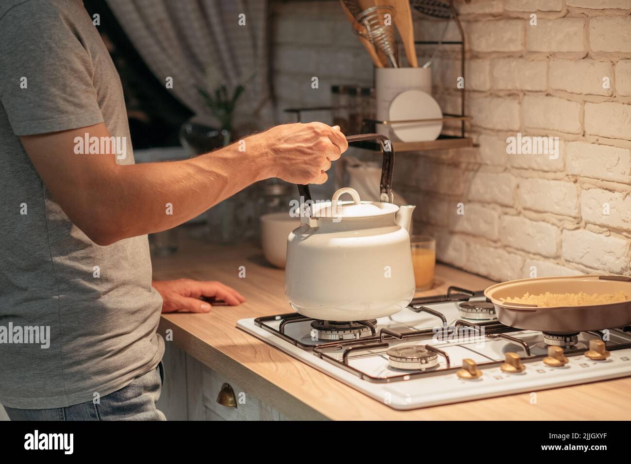 late night tea habit man putting kettle stove Stock Photo