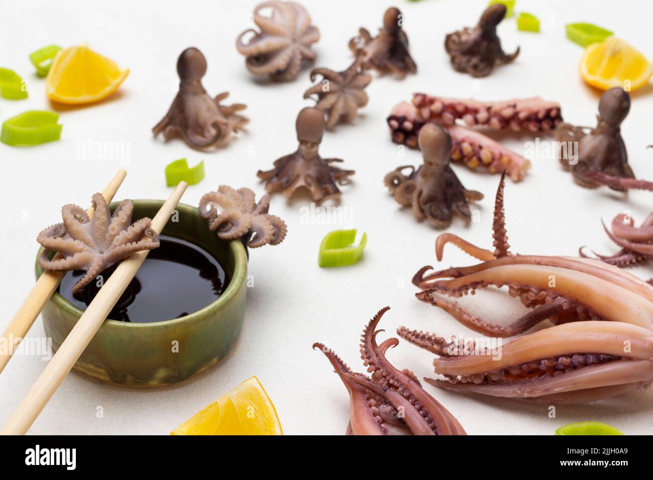Octopus babies on chopsticks and soy sauce. Lemon slices, lemon