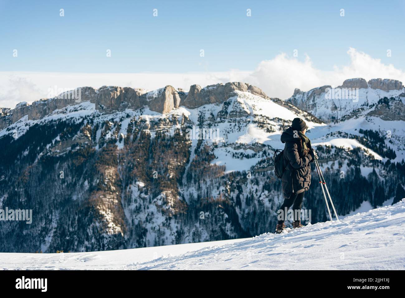 A girl on skis looking at the snow capped mountains in front of her in Switzerland Stock Photo