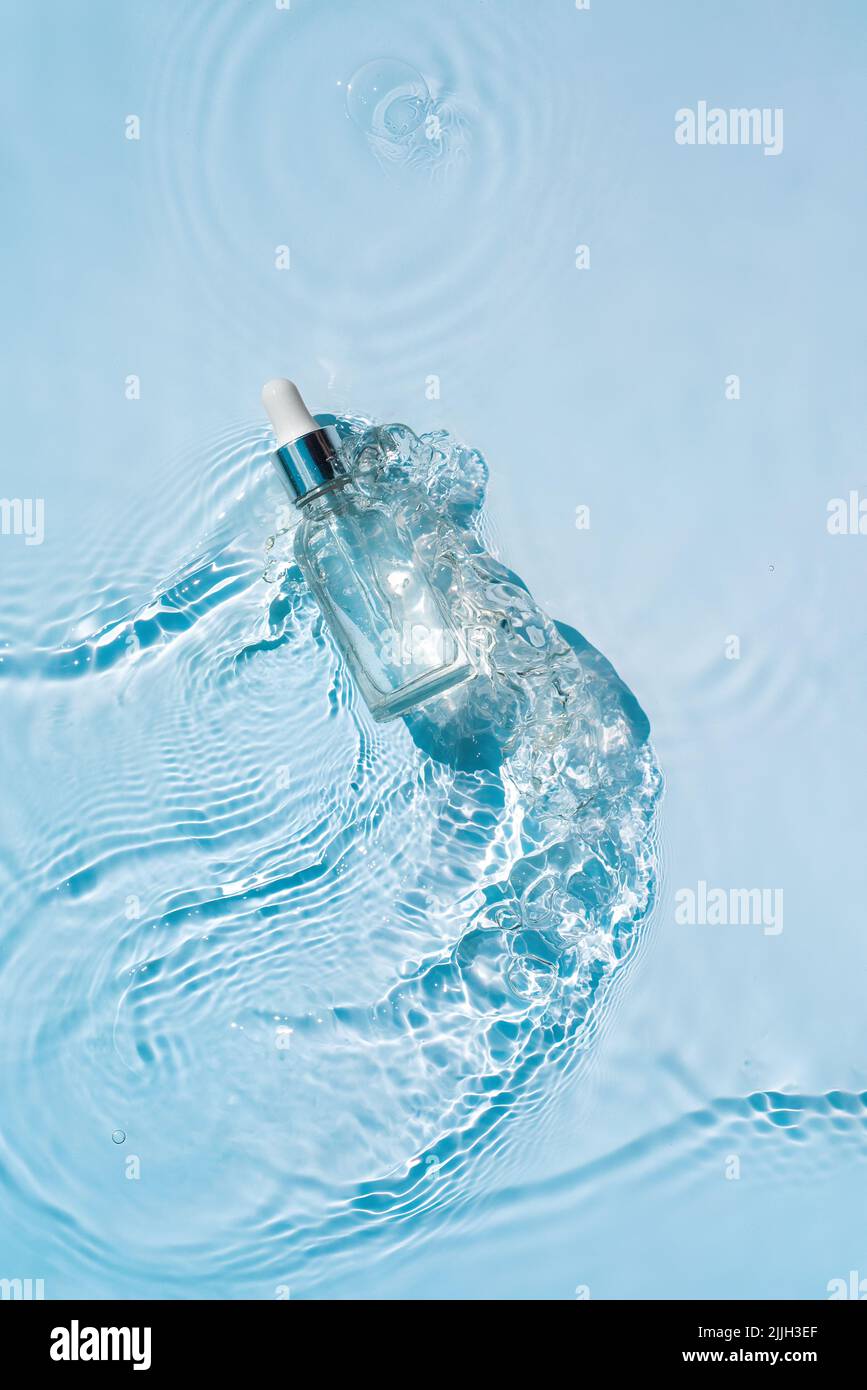 Serum with collagen in transparent bottle with pipette on water background Stock Photo