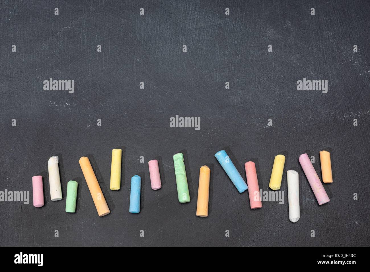 Variety of colored chalk sticks on blackboard. Copy space. Back to school Stock Photo
