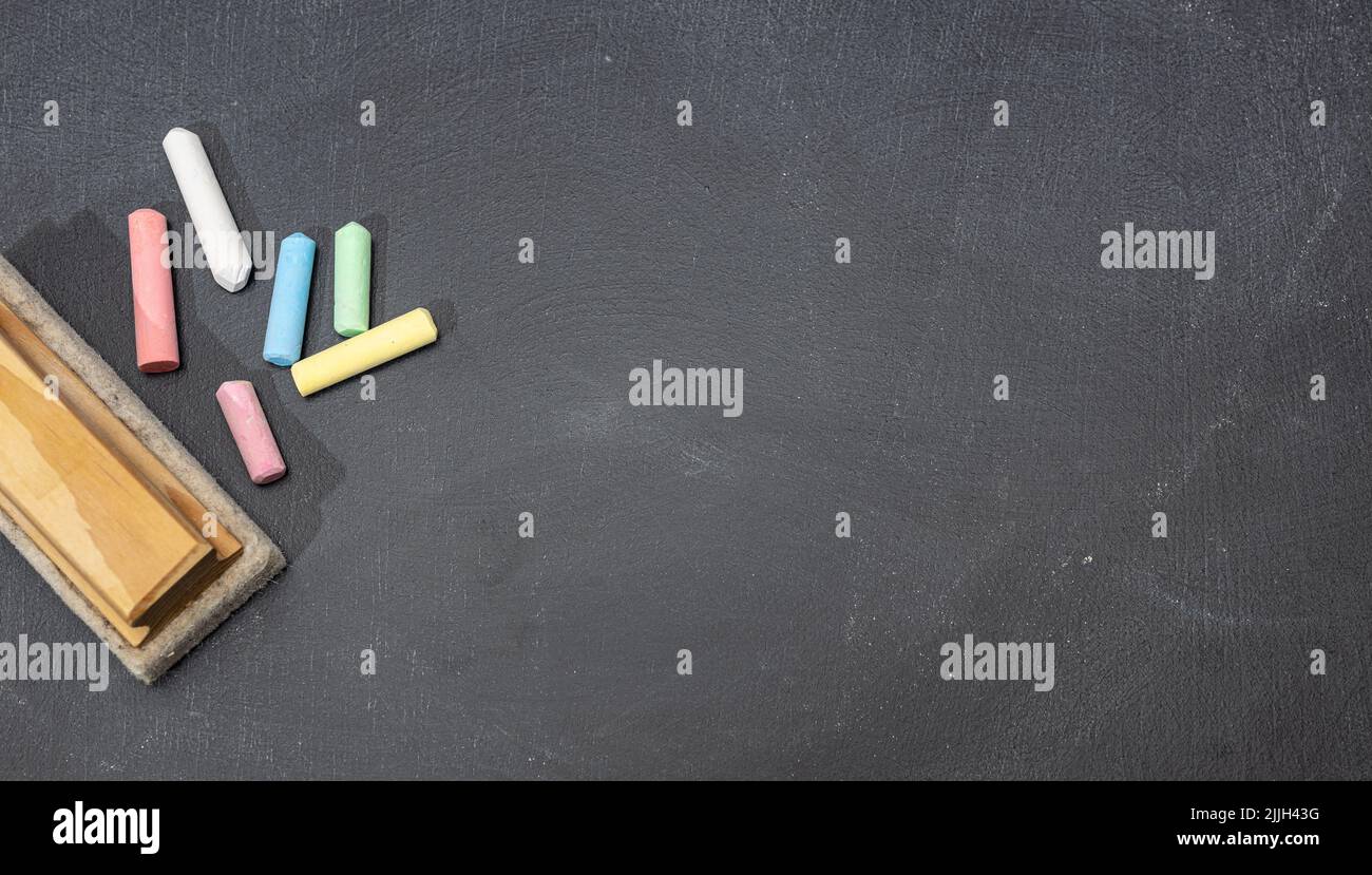 Group of colored chalk sticks and eraser on blackboard. Copy space. Back to school concept Stock Photo