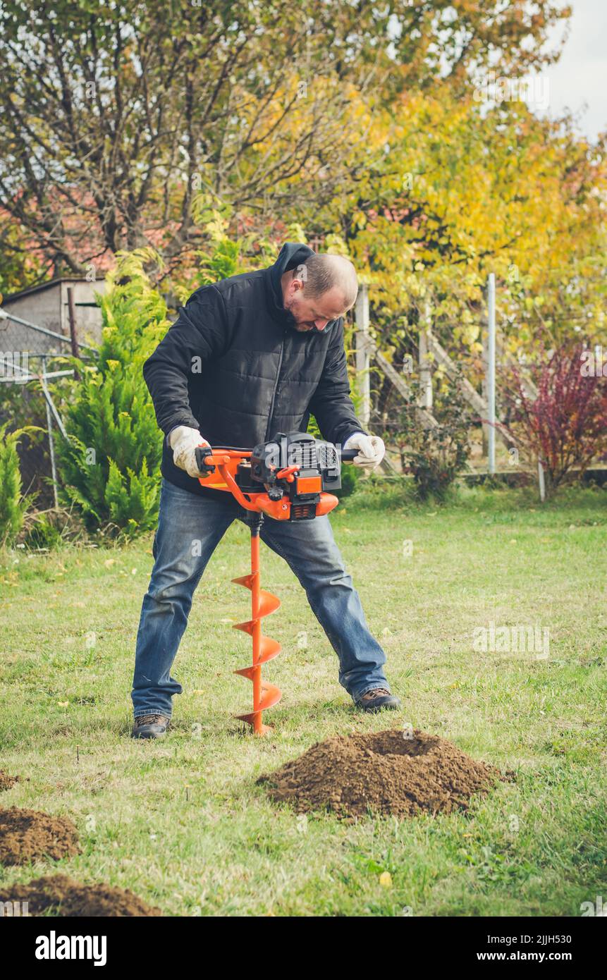 man preparing holes for planting grapes into new vineyard Stock Photo