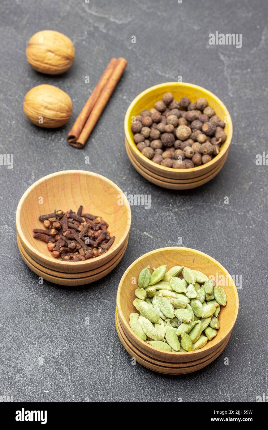Cardamom, cloves and allspice in wooden bowls. Top view. Black