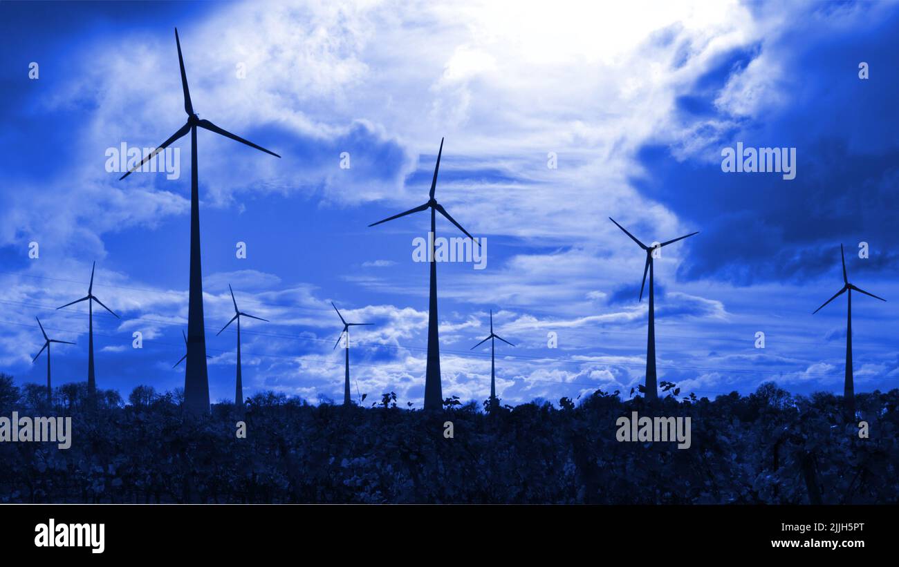 Electrical windmills silhouetted in a dark blue sky Stock Photo