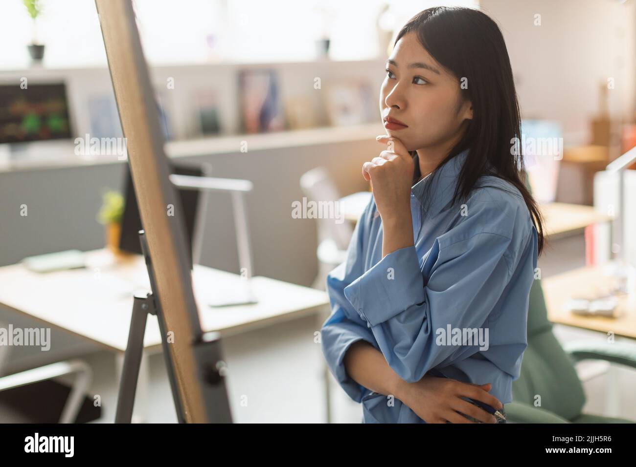 Thoughtful Asian Businesswoman Looking At Whiteboard In Modern Office Stock Photo