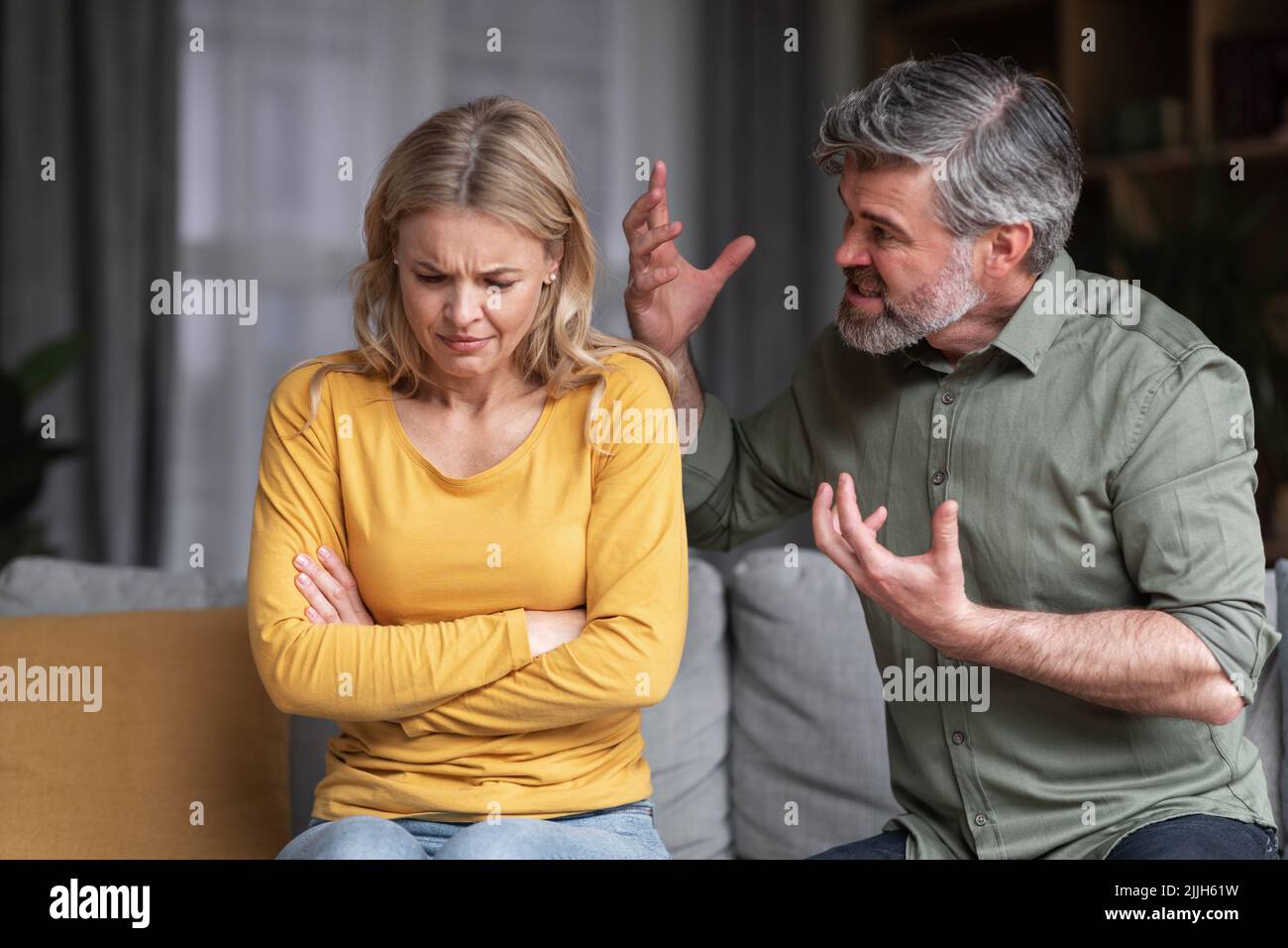 Aggressive Behavior. Portrait Of Abusive Husband Shouting At Wife At Home Stock Photo