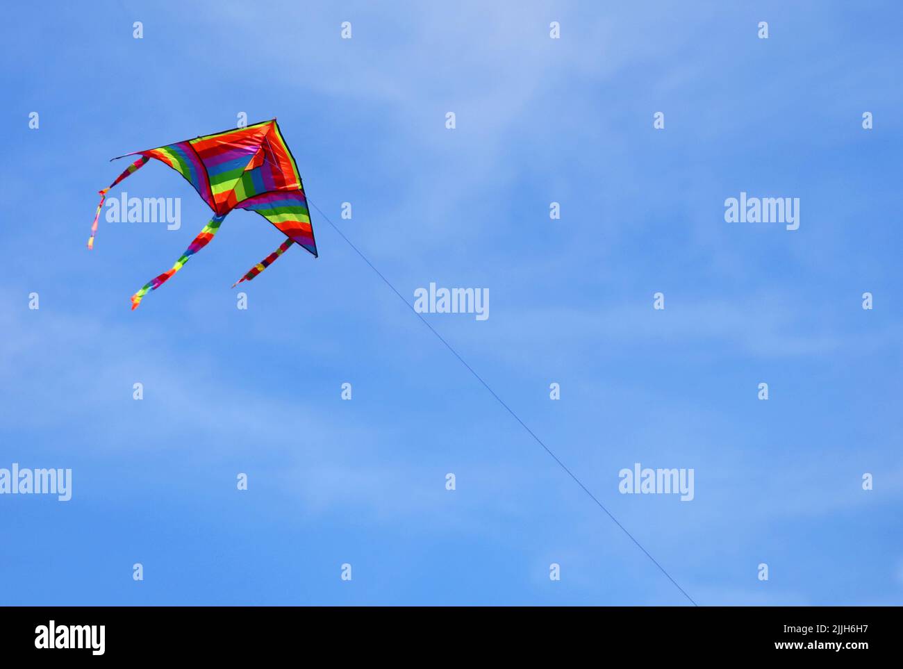 colorful kite with many colors that flies high in the sky tied to a