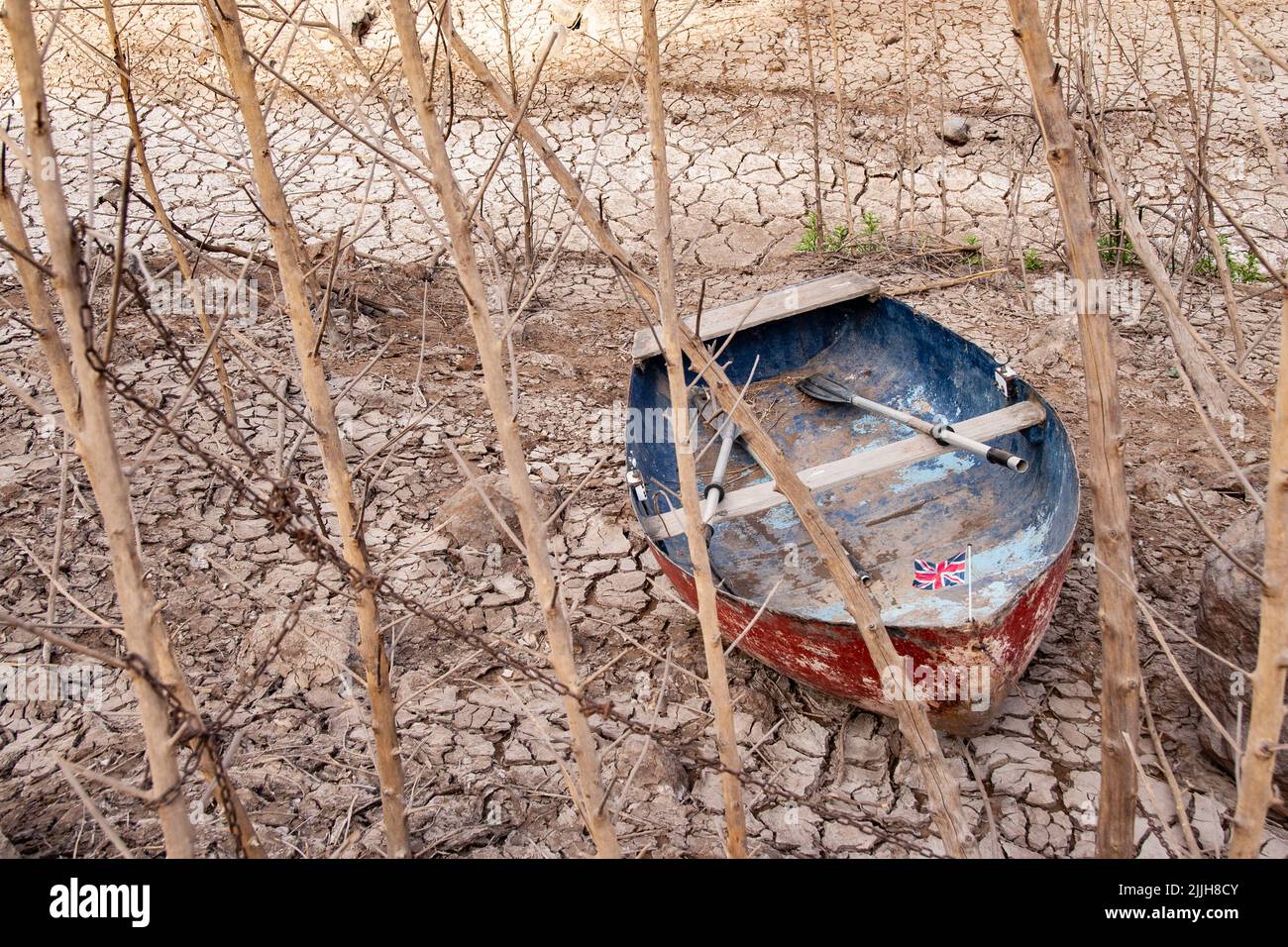 Boat in empty, dry reservoir, lake, cracked earth. Global warming, climate crisis, drought... uk Stock Photo