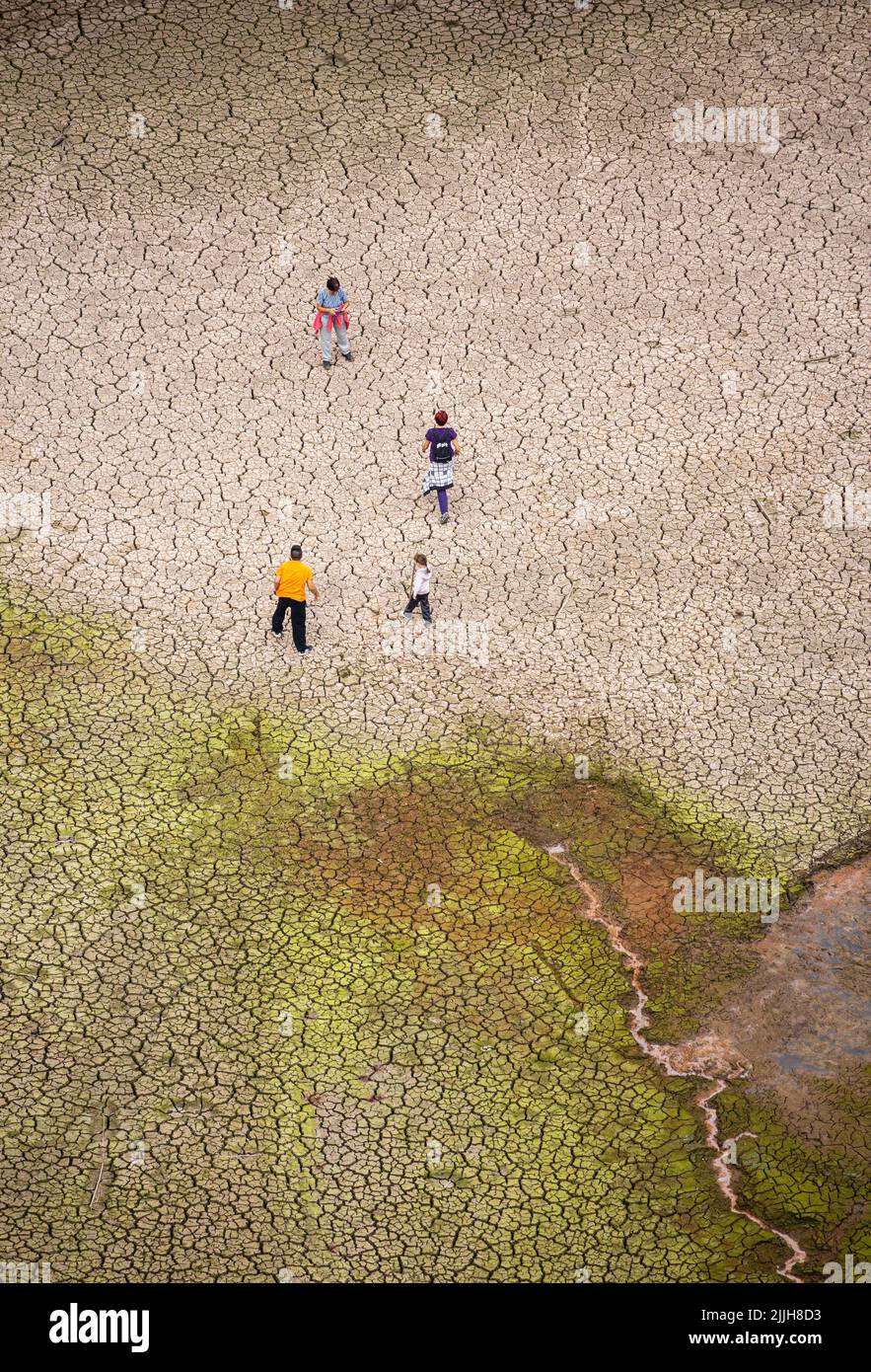 Family walking on cracked earth in empty reservoir, lake. Drought, global warming, climate crisis, water shortage, rising temperatures... Stock Photo