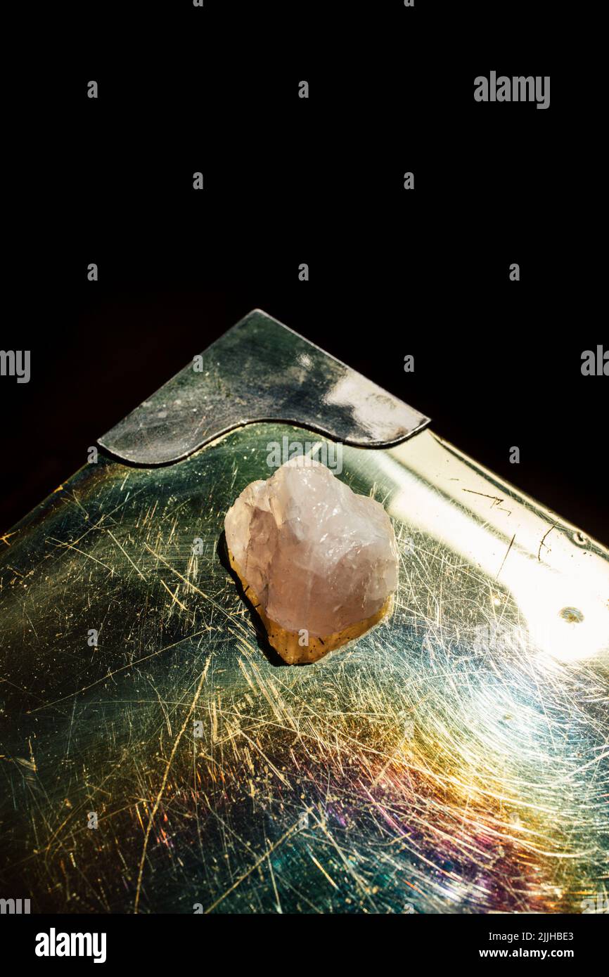 rose quartz on brass iridescent table with black background Stock Photo