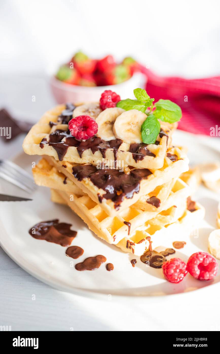 delicious belgian breakfast waffles with strawberries and raspberries and chocolate and banana Stock Photo