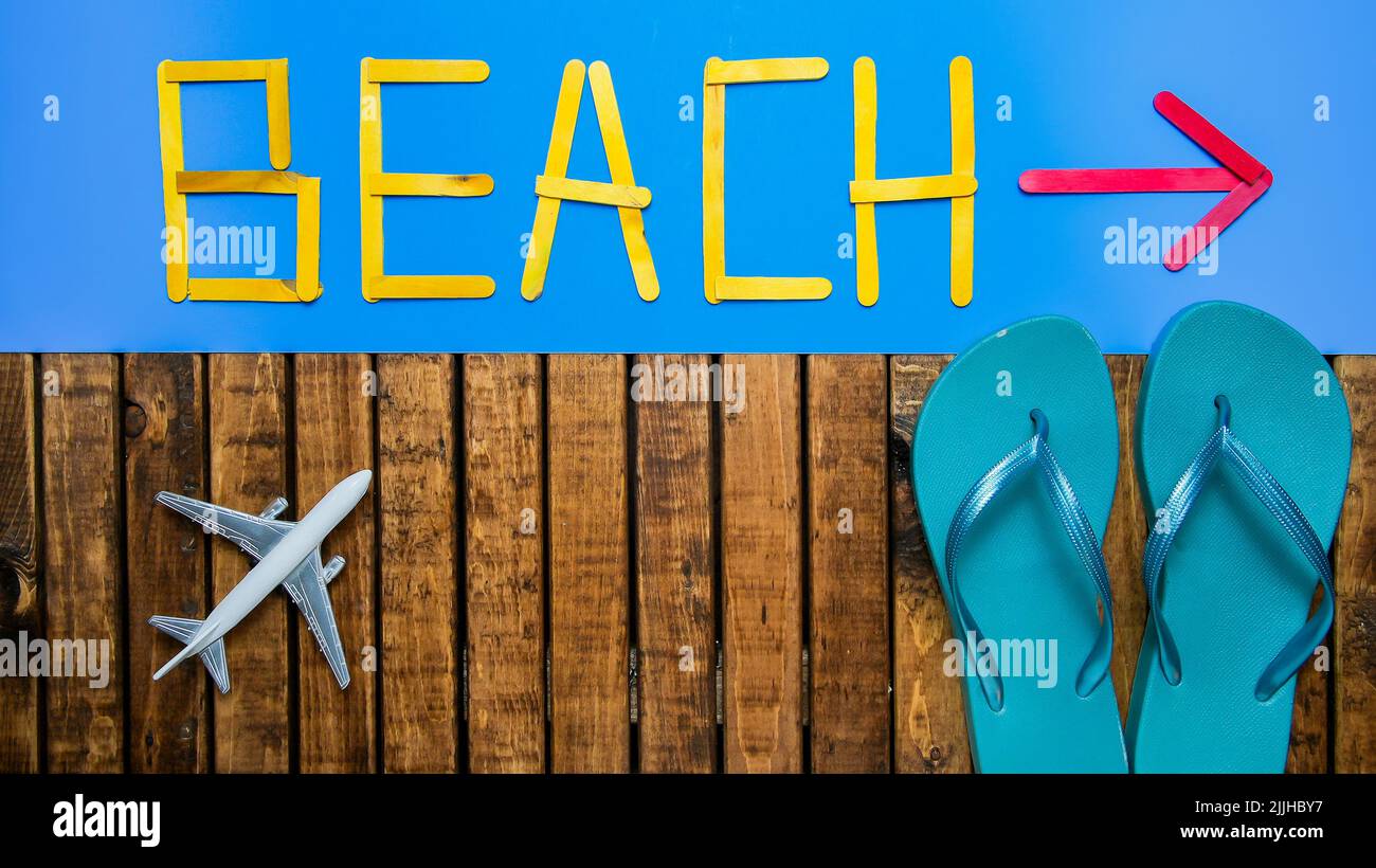 Background with flip flop on wood  and text beach on blue with arrow background Stock Photo