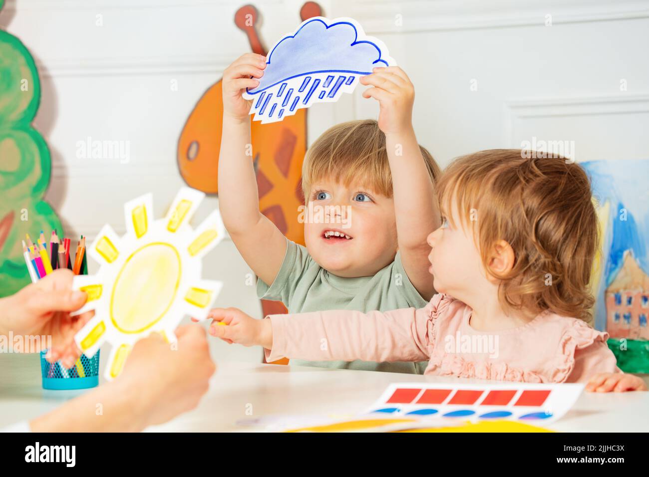 Boy, girl in the class play with weather rain and sun cards Stock Photo