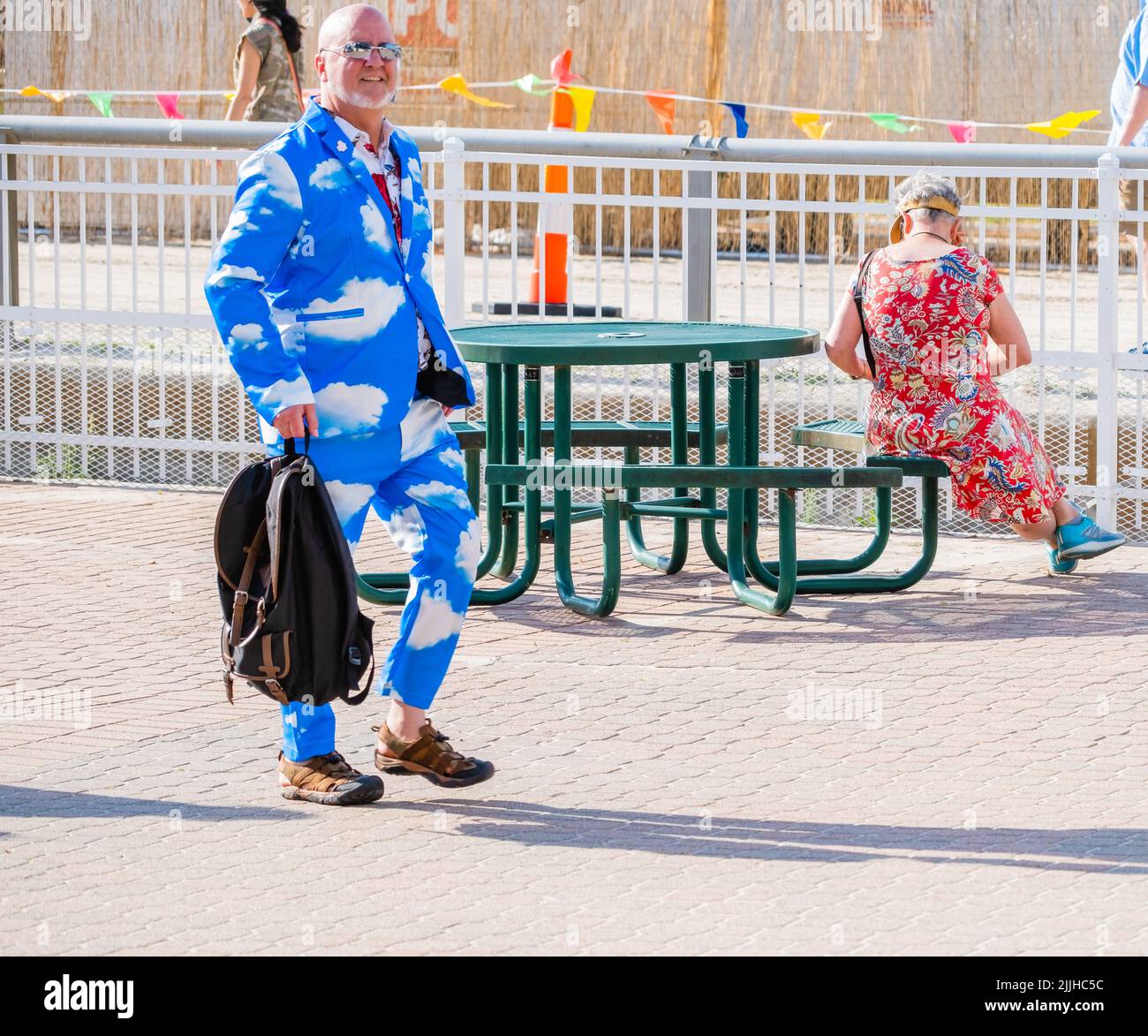 Man with a cloud suit walks past a picnic table at the Fairgrounds during the 2022 New Orleans Jazz and Heritage Festival in New Orleans, LA, USA Stock Photo
