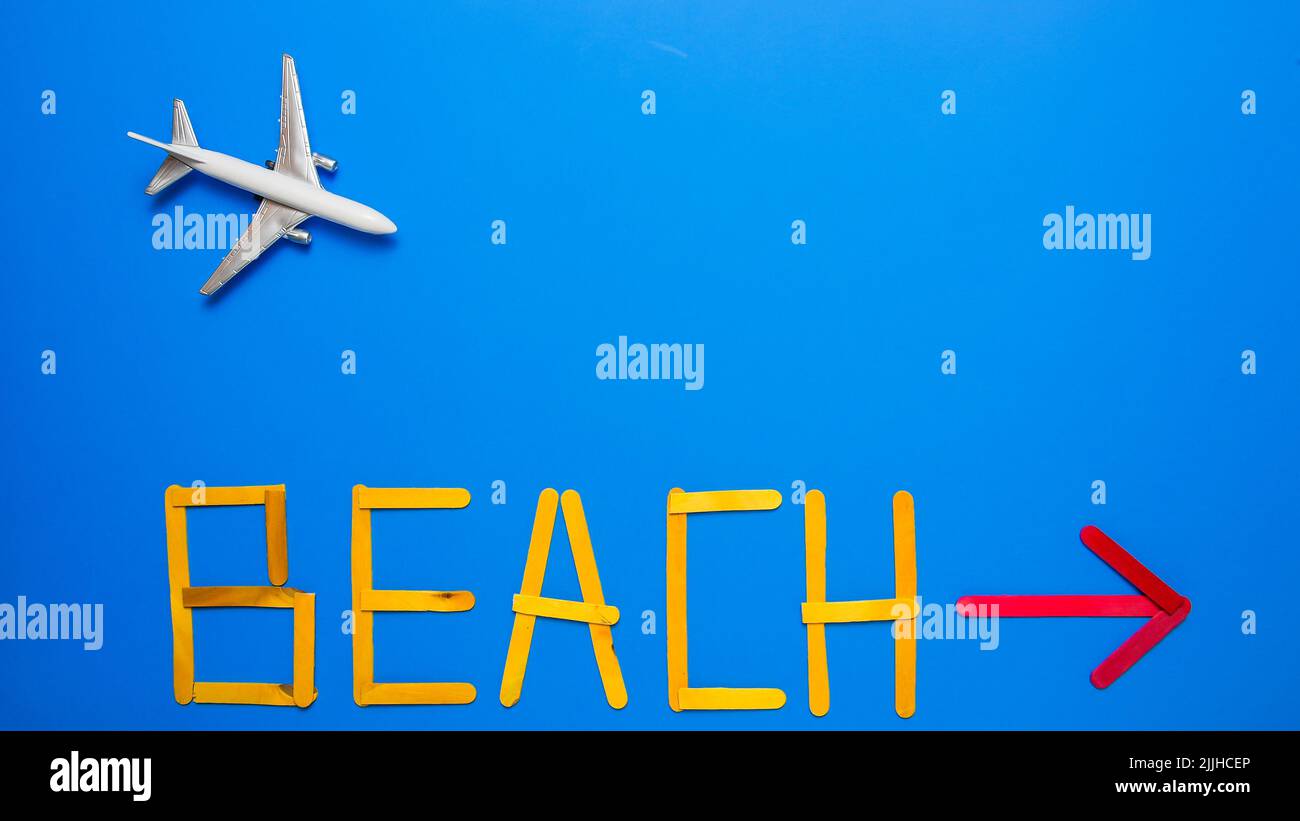 Blue background with toy airplane and text beach with red arrow Stock Photo